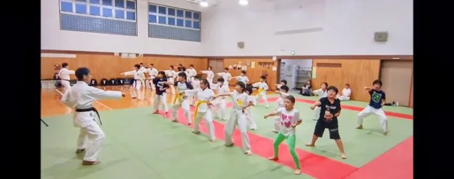 空手の突き動作の稽古をする大人と子供の参加者たち